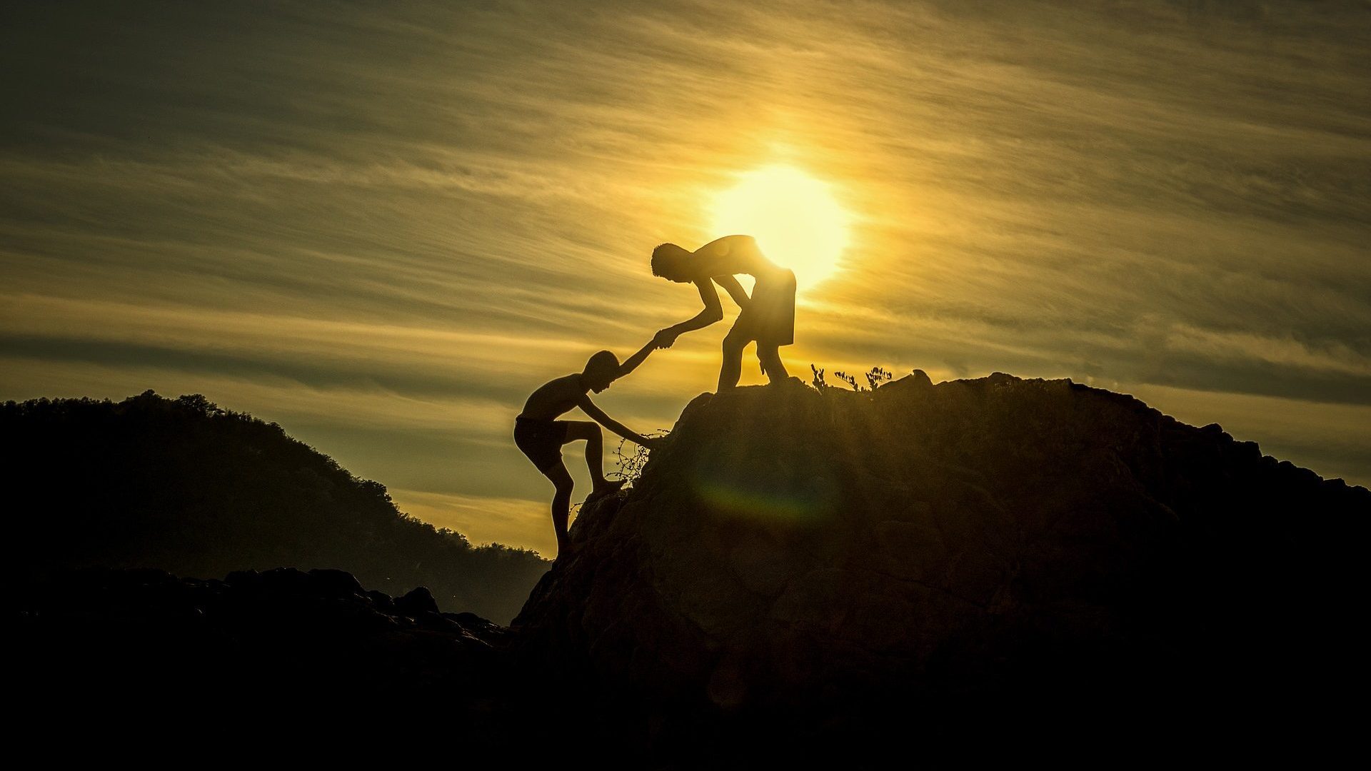Image of one person helping another to climb a hill